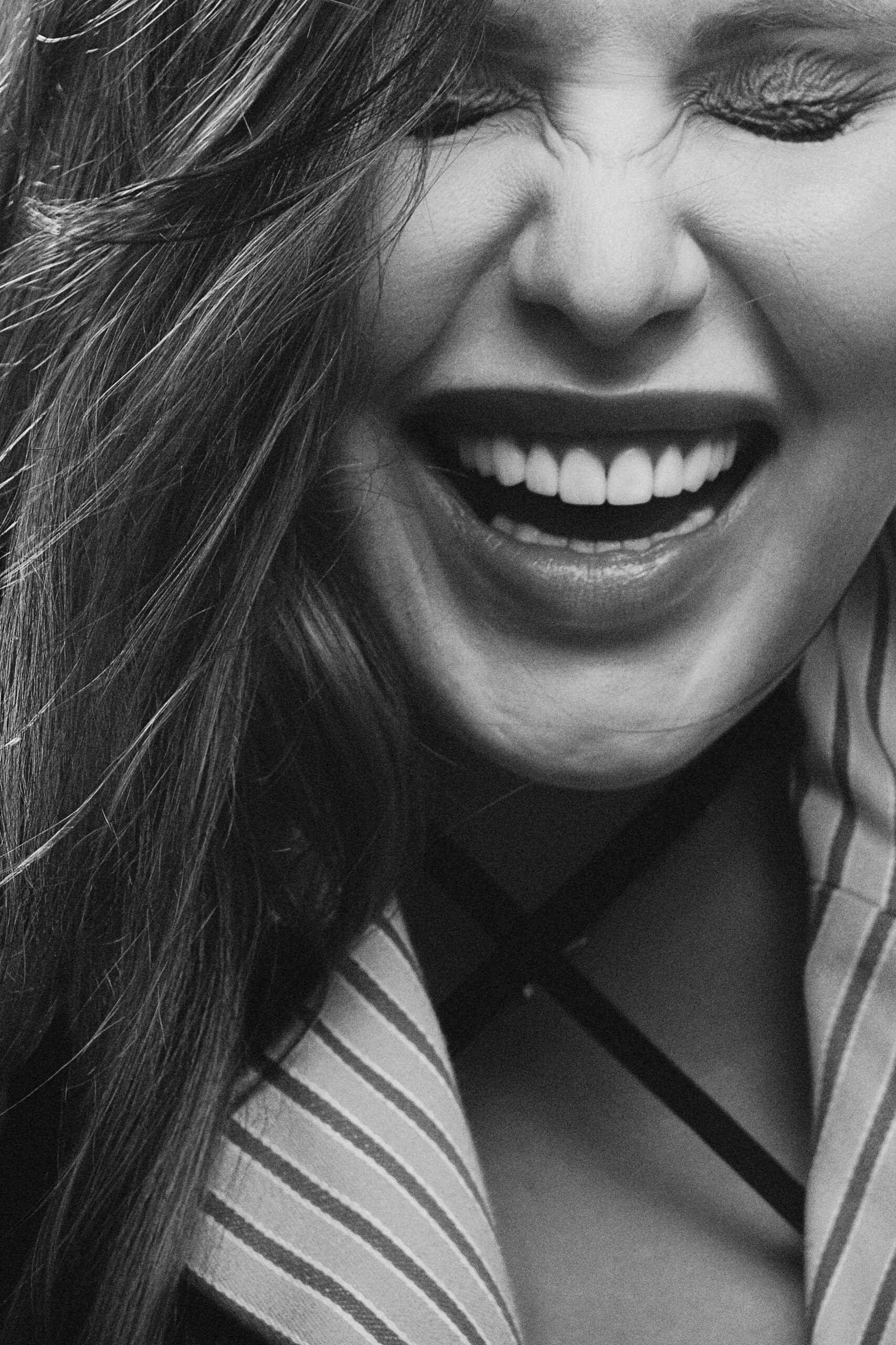 Close-up black and white portrait of a smiling woman expressing joy.