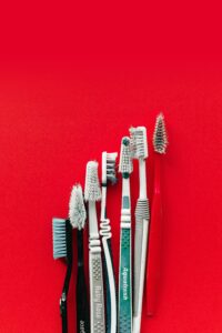 Collection of old and worn toothbrushes on a bright red background, highlighting dental hygiene concepts.